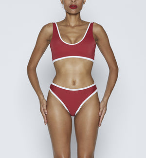 Swimwear Top. Pullover bikini sport bra style top  in ruby red with White contrast binding outline. Bikini bottom. Mid to High Waisted Swimwear bottom in ruby red with White. Medium to full coverage bikini bottom. High Legs swimsuit bottom. Check out our fashion boutique swimsuit online shop. supper soft fabric Nylon/spandex. sport bikini