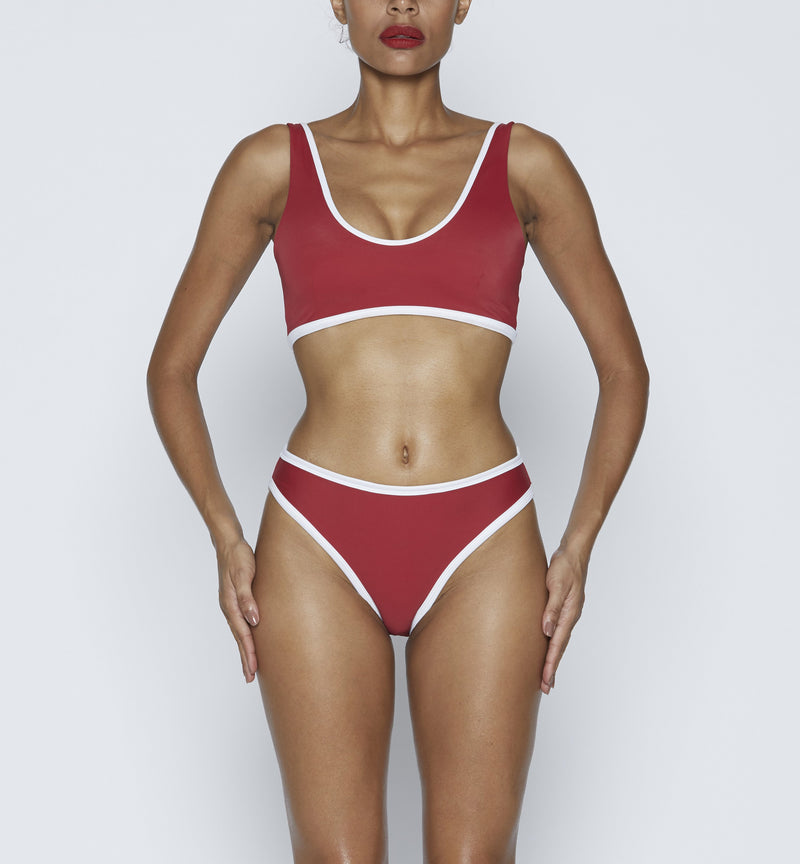 Swimwear Top. Pullover bikini sport bra style top  in ruby red with White contrast binding outline. Bikini bottom. Mid to High Waisted Swimwear bottom in ruby red with White. Medium to full coverage bikini bottom. High Legs swimsuit bottom. Check out our fashion boutique swimsuit online shop. supper soft fabric Nylon/spandex. sport bikini