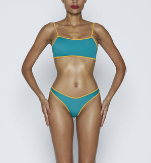 Swimwear Square neck bikini top in emerald green color with yellow contrast binding outline. Adjustable bikini straps. soft swimwear fabric. High legs bikini, high rise bikini bottom. Cheeky coverage swimwear bottom. Shop bikini online.