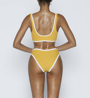 Swimwear Top. Pullover bikini sport bra style top  in vintage yellow with White contrast binding outline. Bikini bottom. Mid to High Waisted Swimwear bottom in yellow vintage with White binding outline. Medium to full coverage bikini bottom. High Legs swimsuit bottom. Check out our fashion boutique swimsuit online shop. supper soft fabric Nylon/spandex. sport bikini